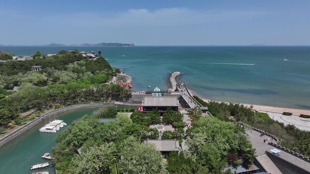 Speedboat cruising through the breakwater at Penglai Pavilion seaside harbor under clear blue sky