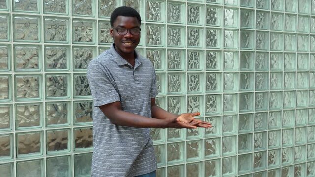 Man shows tricks with his hands in front of glass block wall in the afternoon light
