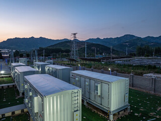 Fototapeta na wymiar Energy storage power station with containerized equipment arrays located in mountainous terrain at dusk