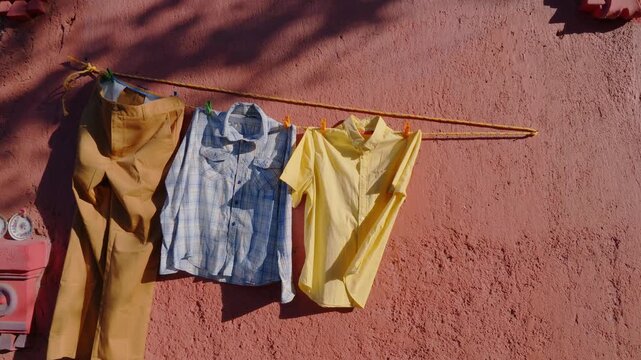 Ropa colgada en una cuerda, venta de segunda mano en un mercado local, vestimenta usada colorida