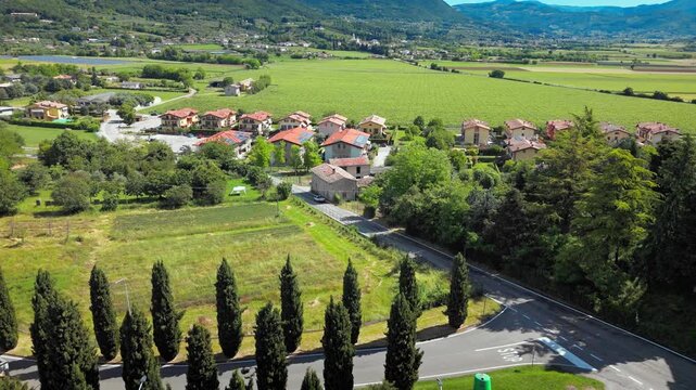 Village streets and houses near vineyard fields in Costermano sul Garda, agricultural landscape with road network, aerial view