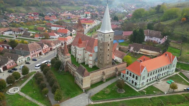 High angle view of the historic Mosna fortified church in Sibiu county. A beautiful 14th-century Gothic Saxon monument surrounded by defensive walls and towers in rural Transylvania, Romania.