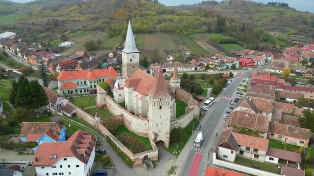High angle view of the historic Mosna fortified church in Sibiu county. A beautiful 14th-century Gothic Saxon monument surrounded by defensive walls and towers in rural Transylvania, Romania.