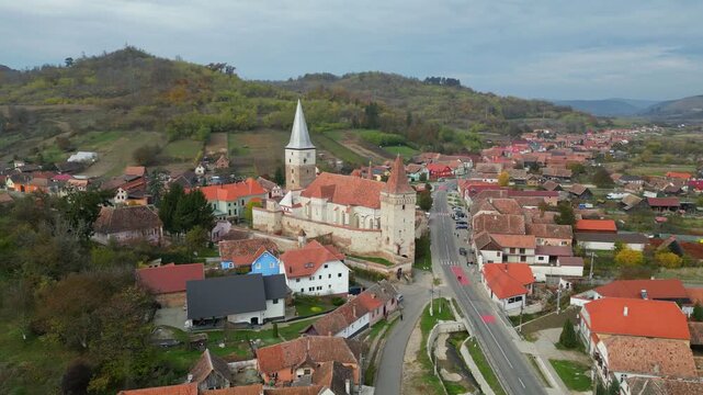 High angle view of the historic Mosna fortified church in Sibiu county. A beautiful 14th-century Gothic Saxon monument surrounded by defensive walls and towers in rural Transylvania, Romania.