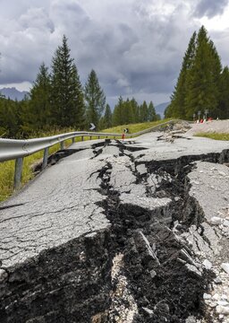 Broken road with cracks in the road surface, broken roadway of a mountain road, Belluno, Italy