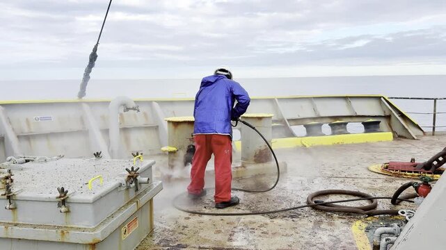 seafarer remove rust from ship bollard use equipment high pressure scaling machine. maintenance of vessel. water spray.