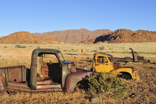 Scrap vehicles at the edge of the desert, Naukluft Mountains at back, Republic of Namibia, Africa