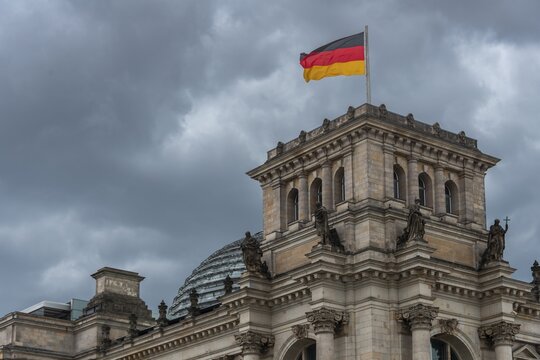 Reichstag with waving German flag at the Spree, government quarter, Berlin, Germany