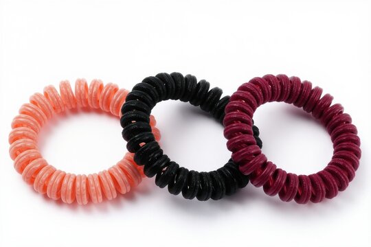 Three spiral hair ties in pink black and burgundy colors sit on a white background. These accessories create ponytail hairstyles without snagging hair.