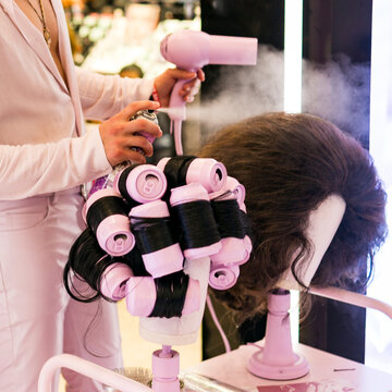 Hair stylist styling a wig and  setting curls with steam rollers