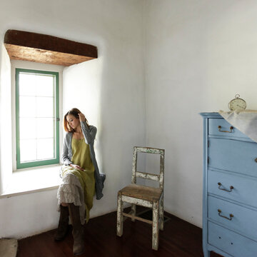 Woman sitting in a quiet sunlit room by a window