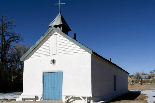 Small white chapel with blue door under a clear sky