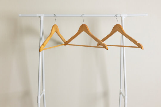 empty clothes hangers on a wardrobe rack on a colored background.