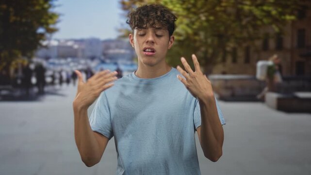 Teenage man touches neck and flicks hands toward chest on pedestrian street by the waterfront; confidence youth attitude.