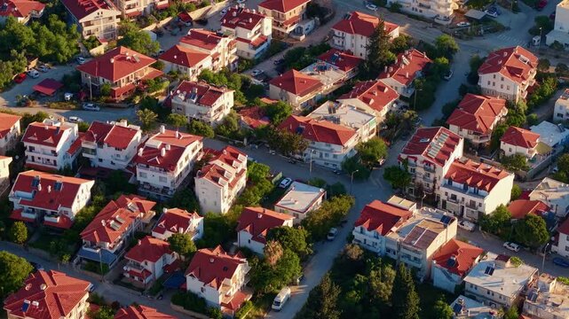 Aerial tracking shot of sunlit suburban houses with red roofs Datcha Turkey.