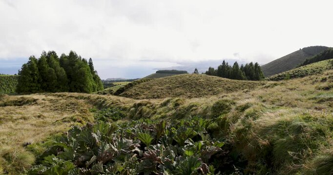 A beautiful landscape with a large hill and the Atlantic Ocean in the background in Sao Miguel, Azores.