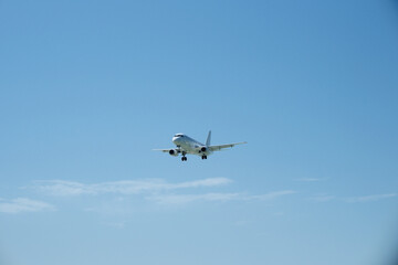 Obraz premium White aircraft on final approach against a blue sky with light clouds