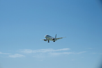 Obraz premium White aircraft on final approach against a blue sky with light clouds