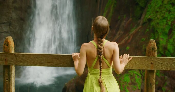 Traveler woman admiring powerful Catarata del Toro cascade from viewpoint in Costa Rica