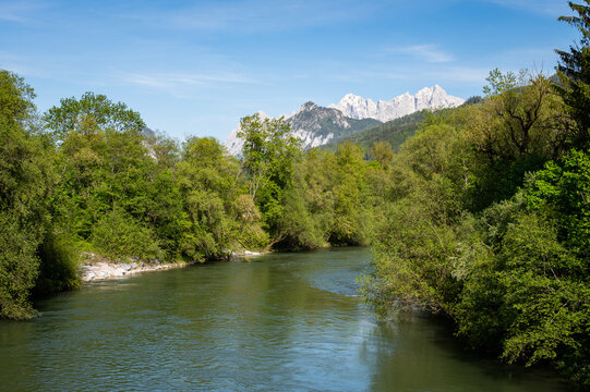 Calm Enns river winds through forest valley with snowy Gesaeuse alpine peaks in distance
