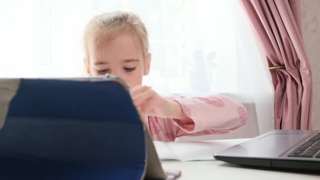 Hybrid learning child studying with laptop and notebook at home