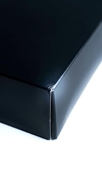 Black fitted bed sheet corner with elastic band on white background for bedroom and home textile products.