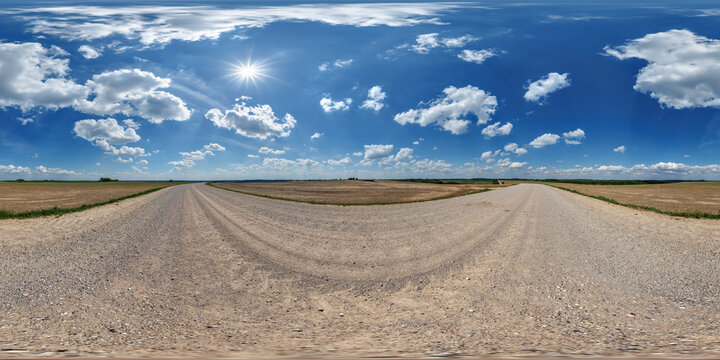 hdri 360 panorama view on gravel country roads among fields with beautiful clouds in sky in equirectangular full seamless spherical projection, ready for VR AR or skydome replacement
