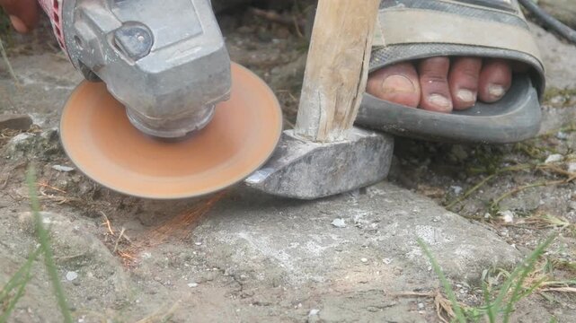 Workers use hand grinders to sharpen or smooth the heads of iron hammers in an open work area.