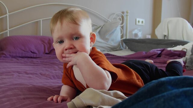 Infant girl on bed play and exploring environment. Child development and family home lifestyle concept