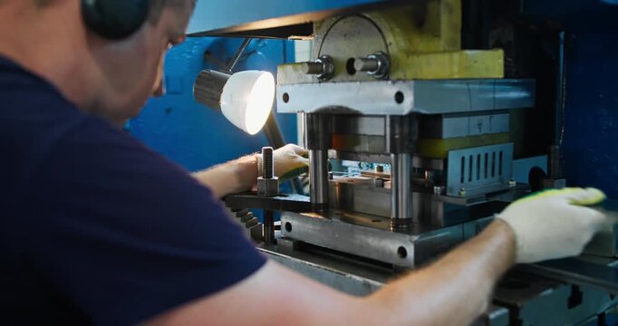 Punch press operator adjusting metal sheet under press tool, precision stamping process in industrial manufacturing