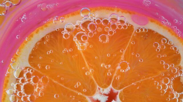 close-up of orange slice in pink bubbly water