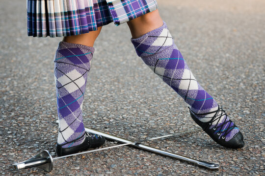Highland dancer performing Scottish sword dance over crossed swords on pavement