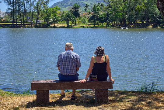Couple sat on bench overlooking a lake, Laguna, Phuket, Thailand