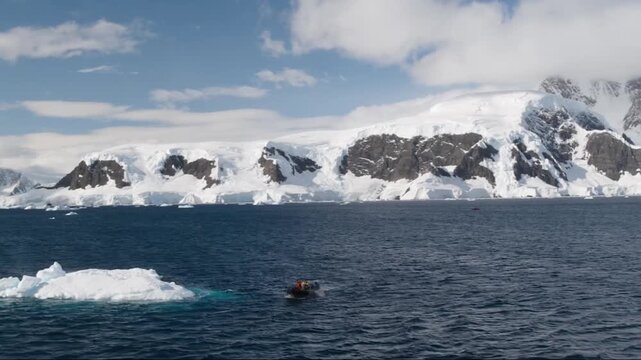 Tourists in a zodiac boat exploring the Antarctic peninsula's icy and mountainous landscape