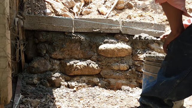 Applying concrete mix over stones and building blocks for a foundation