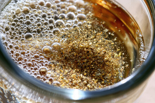 Glass water bubble impurity sediment debris contamination macro closeup texture liquid tap water microscopic floating particle foam surface transparent clear dirty unclean brown gold sharp focus