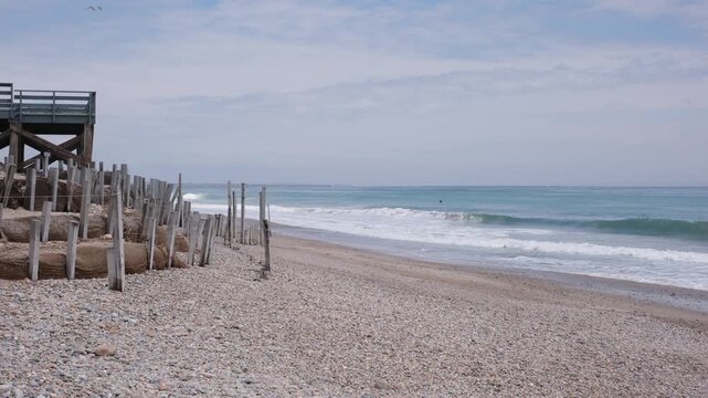 Beach shoreline with wooden pillars and rolling waves.