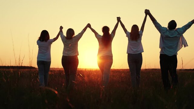 Team teamwork, business group, sun, nature park, sunset. People holding hands, raising hands. People working team. Partnership, helping develop business concept. Business people united by single idea.