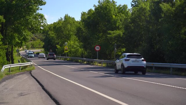Carretera comarcal de la Comunidad de Madrid con varios coches circulando entre el paisaje rural y la vegetaci&oacute;n del entorno.
