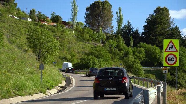 Carretera comarcal de la Comunidad de Madrid con varios coches circulando entre el paisaje rural y la vegetaci&oacute;n del entorno.