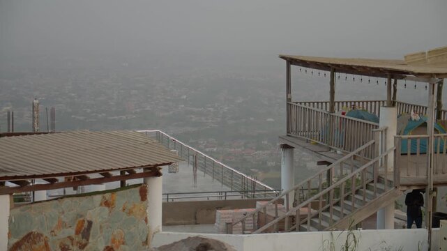 Hazy cityscape of Accra from balcony, urban sprawl and buildings in Ghana under a gray overcast sky on a foggy day