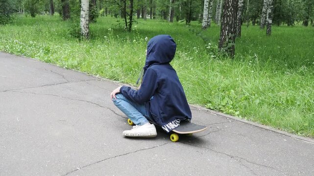 Children playing active sports in a park. A girl learning to skateboard. A girl or child playing skateboarding or surfing outdoors in a park, engaging in extreme sports and protective knee pads