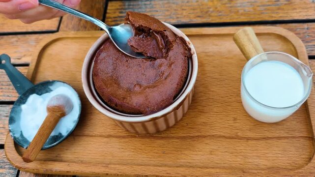 Close Up Video of Person Taking a Spoonful of Warm Chocolate Souffle Lava Cake on a Wooden Tray with Hot Milk and Powdered Sugar, Delicious Sweet Liquid Chocolate Oozing Out