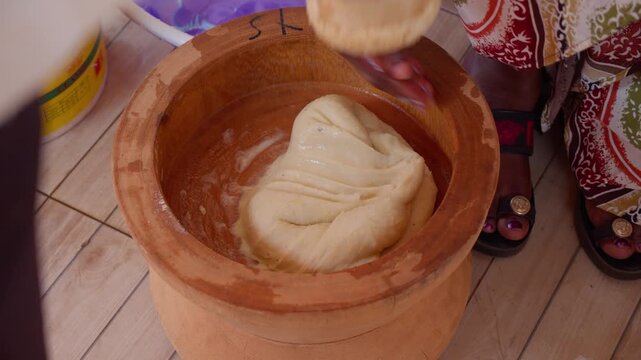 Traditional African woman pounding and kneading dough in wooden mortar for fufu, authentic Ghanaian dish highlighting African culture and cuisine in Ghana