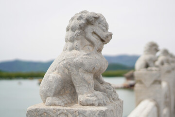 Fototapeta premium Close-up Stone Lion Sculpture on Lakeside Bridge Railing