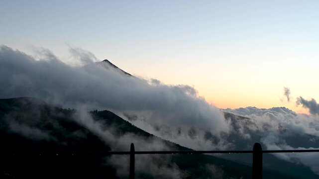 Cinematic close-up of Teide peak above clouds with glowing sunset sky