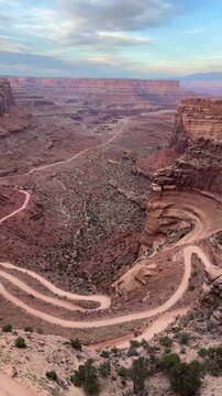 High angle view of the winding switchback dirt road descending into the deep gorge of Shafer Canyon at Canyonlands National Park in Utah.