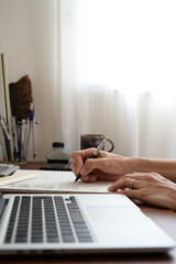 Fototapeta premium Architect sketching design plans at desk with laptop in home office 自宅でノートPCを横に設計図を描く建築士の手元