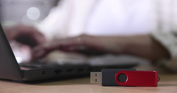 Woman inserting flash drive into laptop at wooden table indoors, selective focus