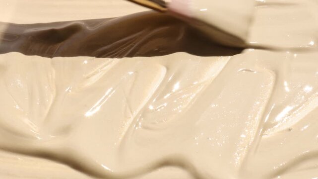 Woman smearing natural clay paste for facial and body care with makeup brush, closeup. Mud therapy